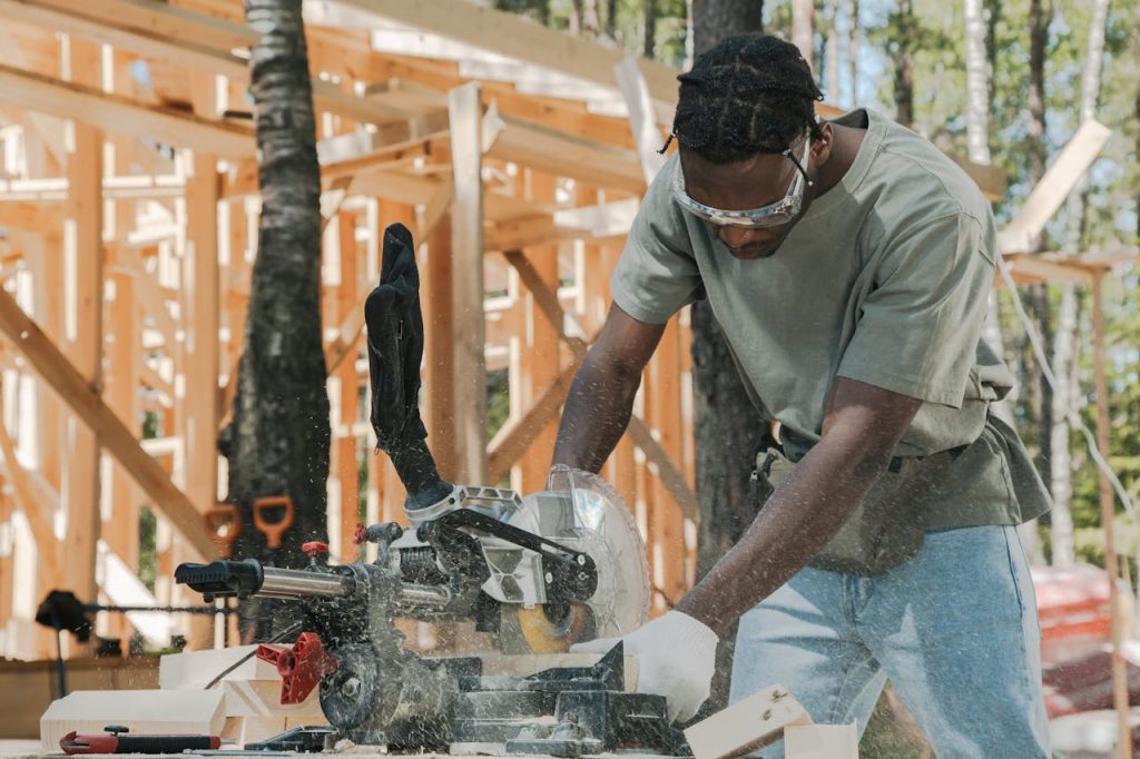 A carpenter using a circular saw at an outdoor construction site.